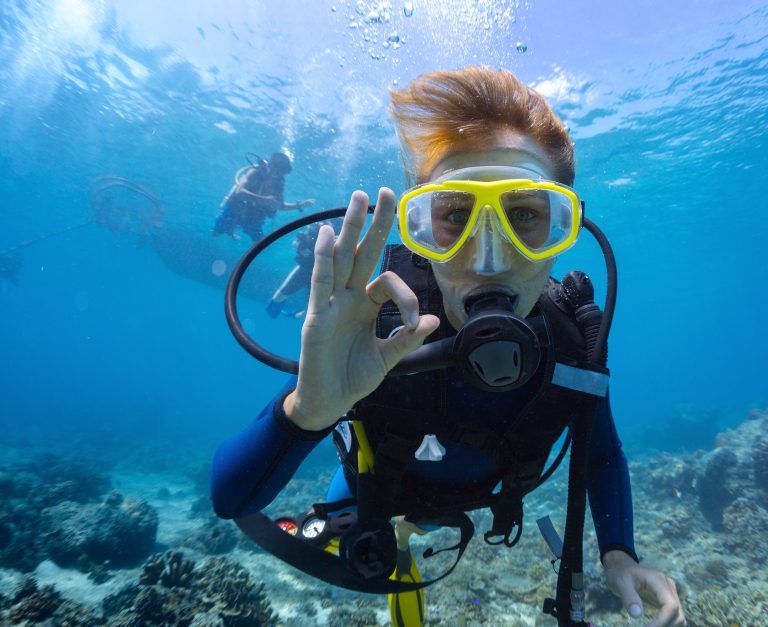 Female scuba diver underwater showing ok signal.